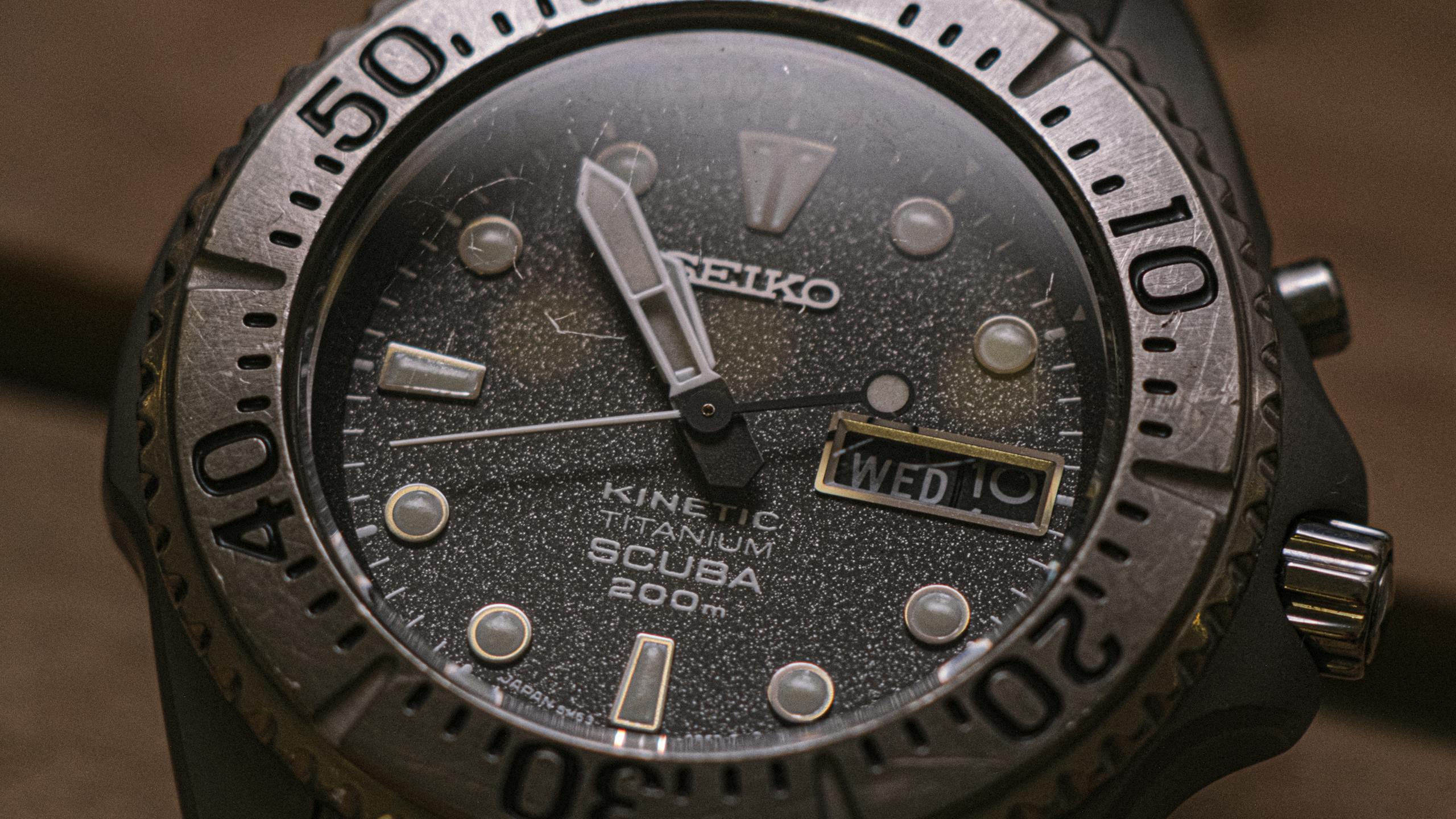 Detailed macro shot of a Seiko Kinetic dive watch displaying time and date with stainless steel casing.