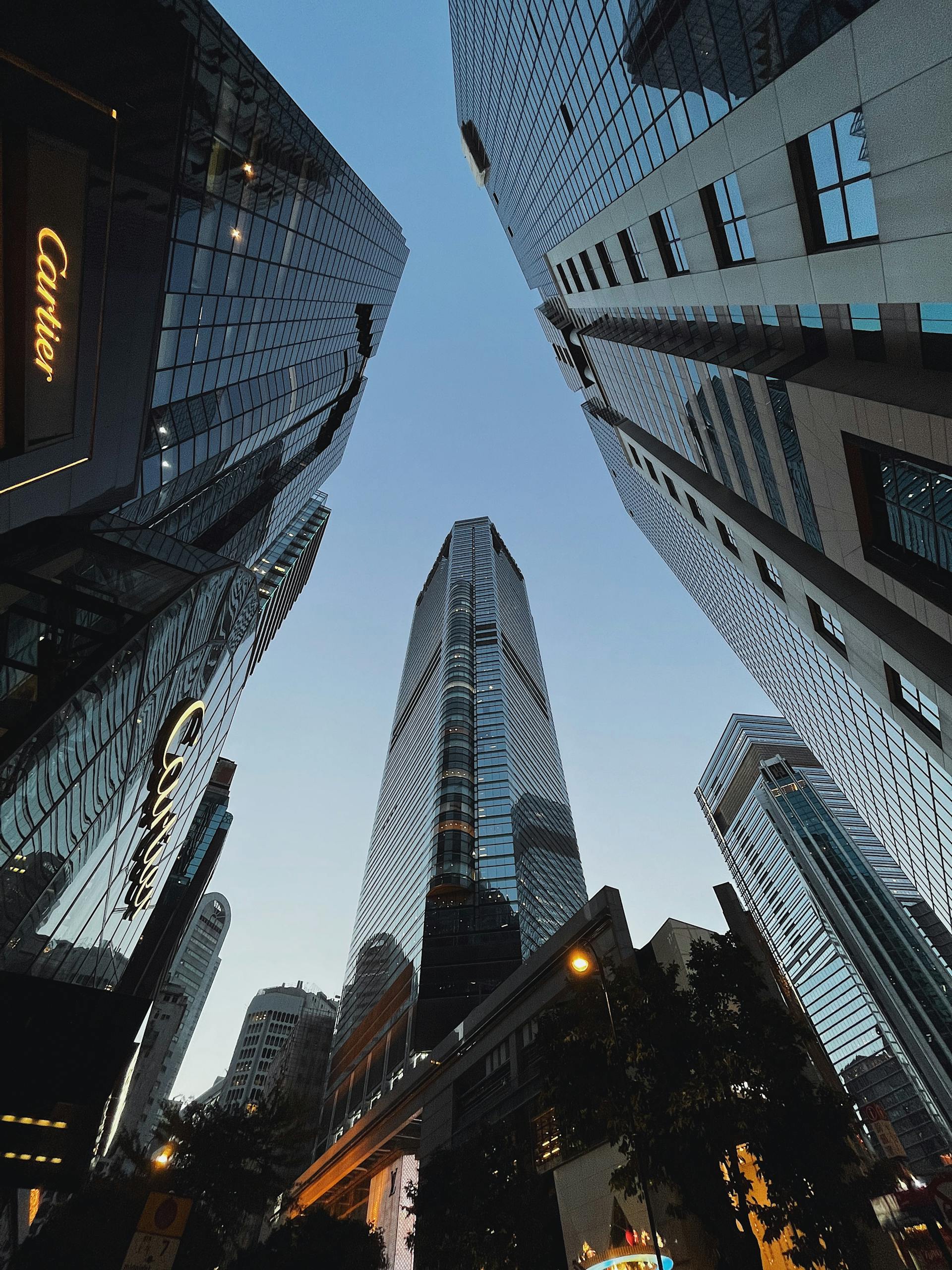 Dramatic upward view of skyscrapers, reflecting the blue sky, showcasing urban architecture.