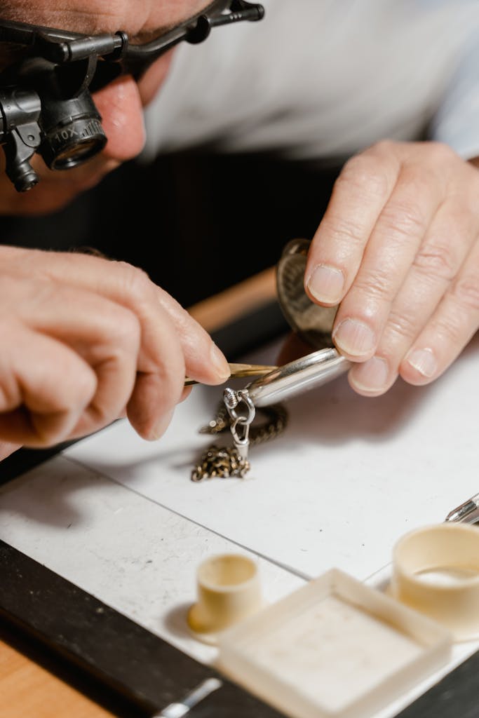 Detailed shot of a craftsman repairing a pocket watch using a magnifying tool on a workshop table.